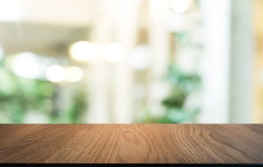 Kafenin soyut bulanık arka planının önündeki boş ahşap masa. Öndeki ahşap tablo ürünlerinizi görüntülemek veya montajlamak için kullanılabilir. Produc gösterimi için modelleyin