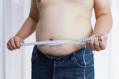 Diyet konseptinde şişman göbekli bir adam. Kilolu adam şişman karnına dokunuyor ve kilo vermek istiyor.