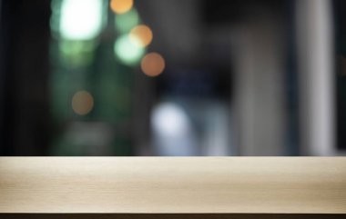 Kafenin soyut bulanık arka planının önündeki boş ahşap masa. Öndeki ahşap tablo ürünlerinizi görüntülemek veya montajlamak için kullanılabilir. Produc gösterimi için modelleyin