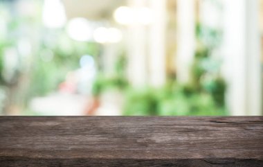 Kafenin soyut bulanık arka planının önündeki boş ahşap masa. Öndeki ahşap tablo ürünlerinizi görüntülemek veya montajlamak için kullanılabilir. Produc gösterimi için modelleyin