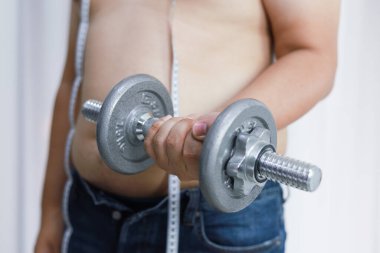 Kilolu bir adam halterle ağırlık kaldırarak egzersiz yapıyor.