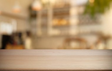 Kafenin soyut bulanık arka planının önündeki boş ahşap masa. Öndeki ahşap tablo ürünlerinizi görüntülemek veya montajlamak için kullanılabilir. Produc gösterimi için modelleyin
