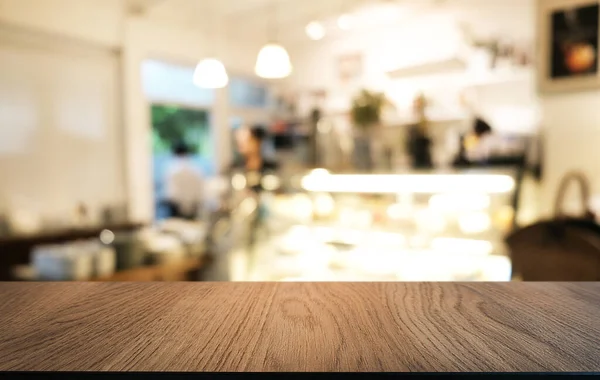 Empty wooden table in front of abstract blurred background of coffee shop . wood table in front can be used for display or montage your products.Mock up for display of produc