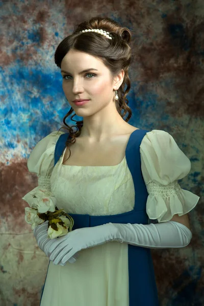 Mooie jonge vrouw in historisch kostuum op blauwe achtergrond — Stockfoto