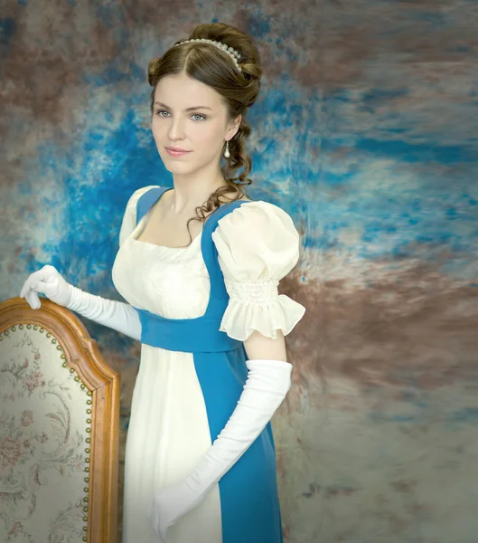 Piękna młoda kobieta w historycznym stroju na niebieskim tle — Zdjęcie stockowe