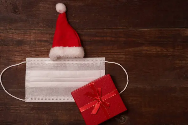 Masque avec chapeau de Père Noël avec cadeau sur fond en bois — Photo