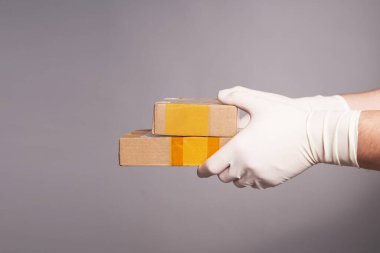 Gri arka planda iki koli olan eldivenli bir adamın elleri.