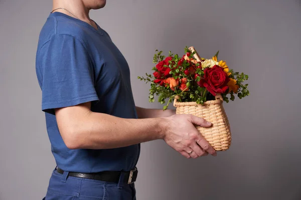 Ręka mężczyzny w rękawiczce z koszem kwiatów na szarym tle — Zdjęcie stockowe