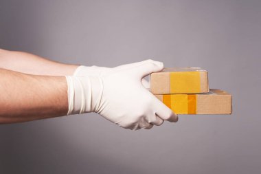 Gri arka planda iki koli olan eldivenli bir adamın elleri.