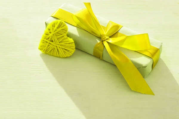 Kraft ajándék doboz gyönyörű sárga szalag és szív világos fa háttér — Stock Fotó