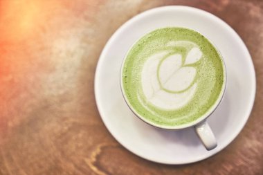 Ahşap arka planda bir fincan kibrit latte ve fotokopi alanı olan bir kafede peçete.