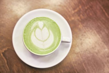 Ahşap arka planda bir fincan kibrit latte ve fotokopi alanı olan bir kafede peçete.