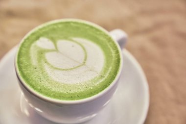 Ahşap arka planda bir fincan matcha latte ve fotokopi alanı olan bir kafede bej peçete. Yüksek kalite fotoğraf