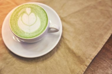 Ahşap arka planda bir fincan matcha latte ve fotokopi alanı olan bir kafede bej peçete. Yüksek kalite fotoğraf