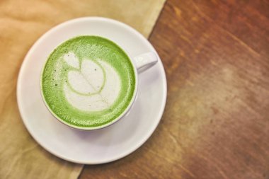 Ahşap arka planda bir fincan matcha latte ve fotokopi alanı olan bir kafede bej peçete. Yüksek kalite fotoğraf