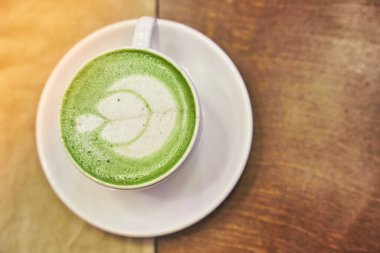 Ahşap arka planda bir fincan matcha latte ve fotokopi alanı olan bir kafede bej peçete. Yüksek kalite fotoğraf