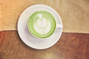 Ahşap arka planda bir fincan matcha latte ve fotokopi alanı olan bir kafede bej peçete. Yüksek kalite fotoğraf