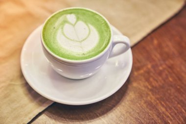 Ahşap arka planda bir fincan matcha latte ve fotokopi alanı olan bir kafede bej peçete. Yüksek kalite fotoğraf