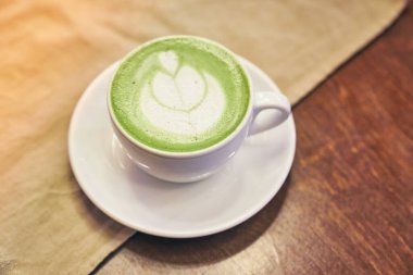 Ahşap arka planda bir fincan matcha latte ve fotokopi alanı olan bir kafede bej peçete. Yüksek kalite fotoğraf