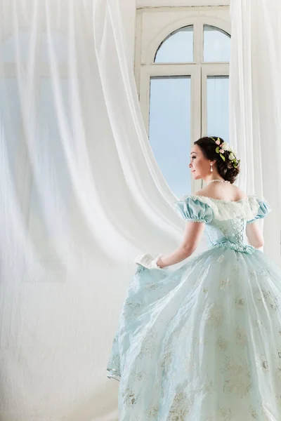 Hermosa mujer de pelo oscuro elegante en vestido histórico en el fondo con ventana —  Fotos de Stock