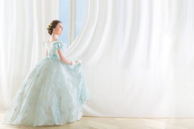 Arkaplanda pencereli, tarihi bir 1867 elbisesi olan zarif, koyu renk saçlı bir kadın. Yüksek kalite fotoğraf