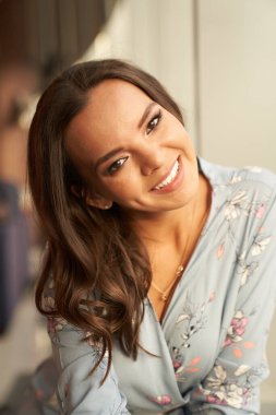 Güzel, genç, mutlu bir kadın arka planda fotokopi çekerek gülümsüyor.