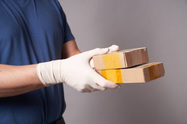 Gri arka planda iki koli olan eldivenli bir adamın eli.