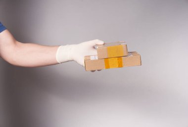 Gri arka planda iki koli olan eldivenli bir adamın eli.