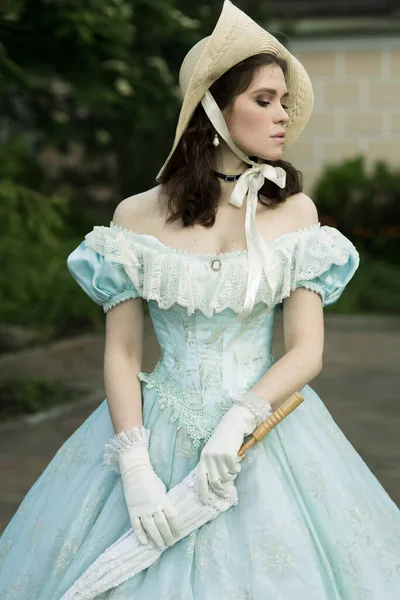 Una hermosa joven con un vestido azul histórico de 1860 años. Diseño de cubierta de libro. Imagen de stock