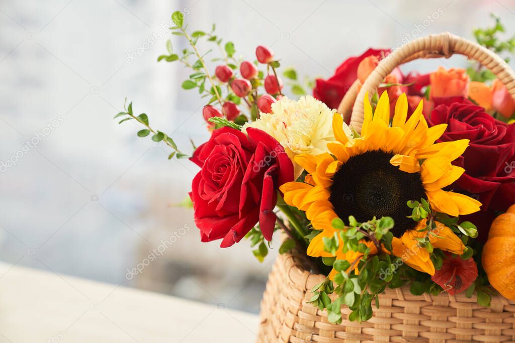 Mixed autumn flowers in basket, bouquet is on the windowsill with copy space. 