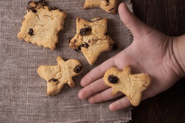 Sağlıklı ahşap arka planda ev yapımı kurabiyeler ve çocuk eli.