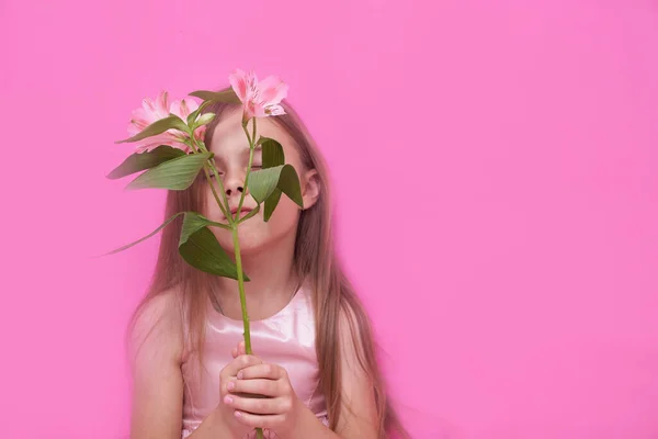 Alstroemeria en la mano de las niñas sobre un fondo rosa — Foto de Stock