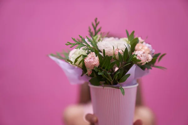 Una niña en vestido rosa con ramo de flores de mezcla, se escondió detrás de las flores. — Foto de Stock