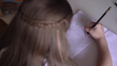 Küçük kız ders çalışıyor, dersler alıyor, çocuk defterdeki hücreleri çiziyor..