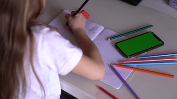 Kleines Mädchen lernt, unterrichtet, benutzt ein Handy mit grünem Bildschirm — Stockvideo
