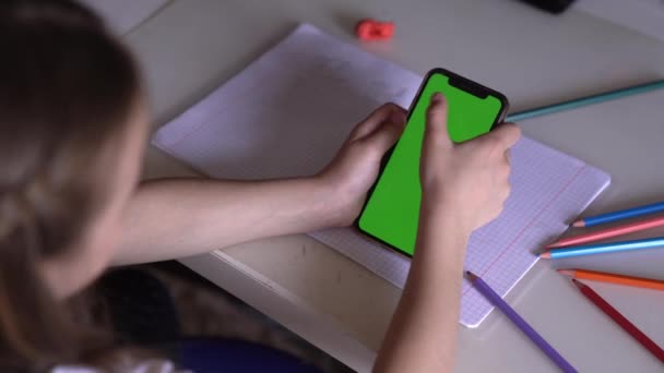 Ein kleines Mädchen spielt auf ihrem Handy statt zu Hause in der Schule. — Stockvideo