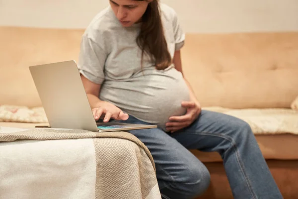 Schwangere sitzt zu Hause am Computer und sucht Informationen — Stockfoto