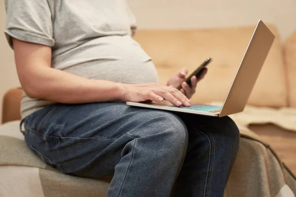 Schwangere mit Handy zu Hause sitzt am Computer, Online-Shopping — Stockfoto