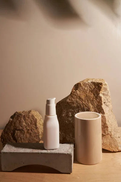 Bottiglia bianca su fondo beige sul podio con pianta tropicale — Foto Stock