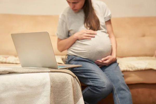 Schwangere sitzt zu Hause am Computer und sucht Informationen — Stockfoto