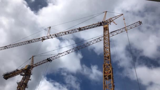 Twee gele hijskranen in de blauwe lucht met prachtige wolken, bouwwerkzaamheden — Stockvideo