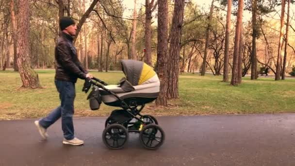 Video al rallentatore di papà che cammina con il neonato nel passeggino la sera — Video Stock