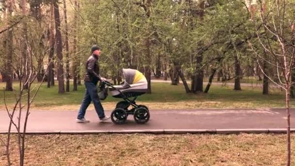 Långsam video av far promenader med nyfödda barn i barnvagn på kvällen — Stockvideo