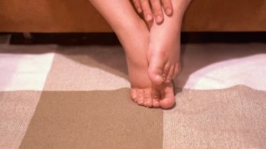 Bir kadın şişmiş bacaklarına eliyle dokunur. Hamileliğin son aşamaları.