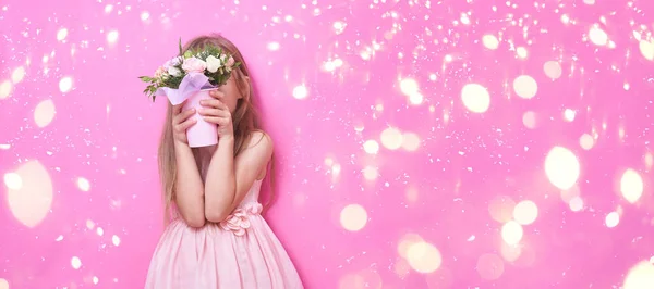 Een klein meisje in roze jurk met boeket bloemen, verborgen achter de bloemen. — Stockfoto