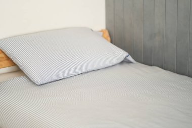 Yatak, odanın arka tarafındadır. Yatak hazırlandı. Gri renk.