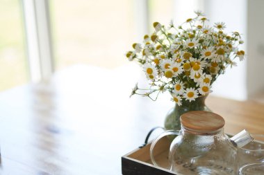 Pencerenin yanındaki mutfak masasının üzerinde duran cam vazoda duran güzel papatya çiçekleri. Ev içinde çiçek düzenleme, dekor