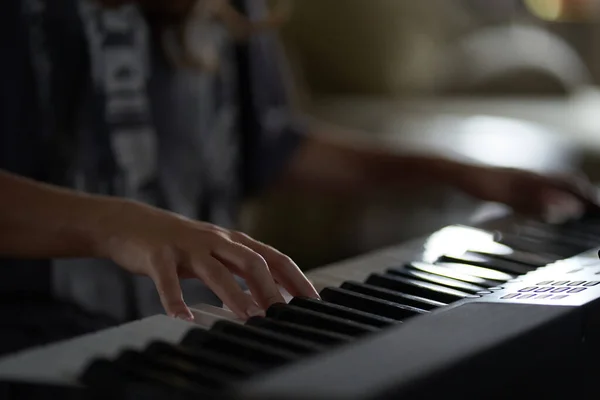 The musicians hands on the synthesizer. A cropped image of a person playing a synthesizer. Side view