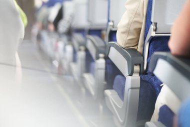 Uçağın bir tarafında bir sıra koltuk. İnsanlar koridordaki yolcu kabinindeki kameraya sırtlarını dönerek oturuyorlar. Kulübede gün ışığı. Kopyalayacak yer de var. Yüksek kalite fotoğraf