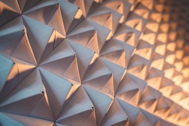 Üçgenlenmiş kağıt arka planı. İlginç ışık ile hacimsel şekiller.